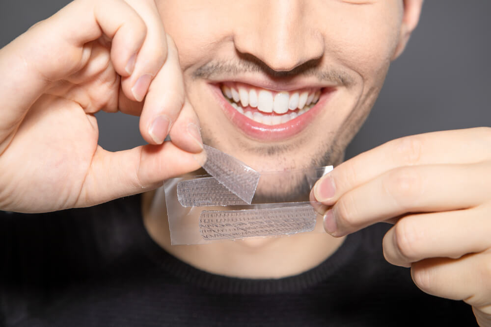 Smiling Man Using Teeth Whitening Strips